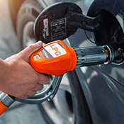 Hand holding gas pump that is inserted into gas tank