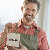 Man in apron holding up Open sign